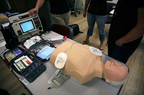 Paramedic students learn how to manage cardiac arrests through simulation. This includes a manikin, cardiac monitor/defibrillator, a cardiac rhythm generator, mock drugs, airway management equipment, and IV supplies. Photo courtesy of Flickr