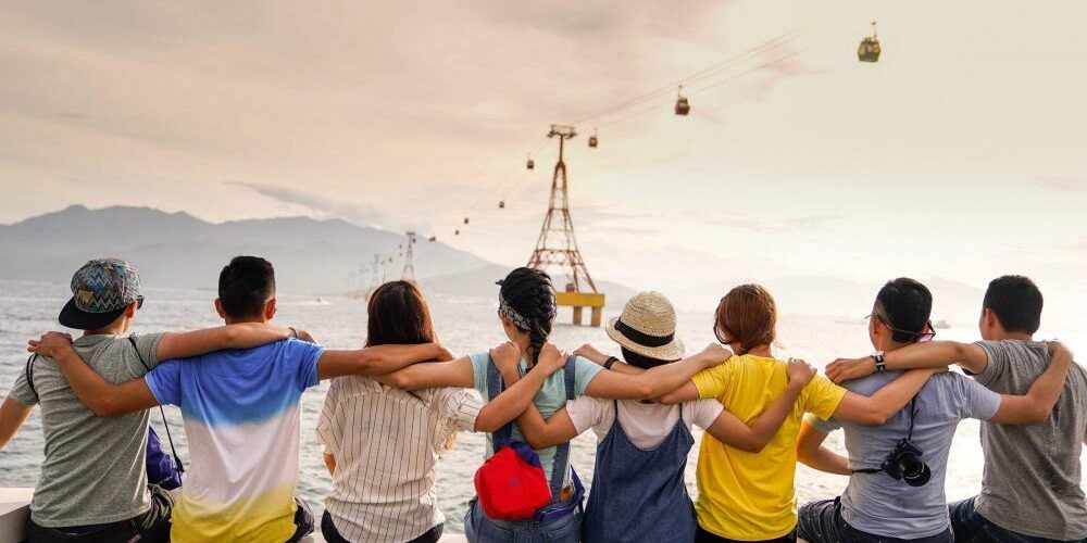People arm in arm by the water