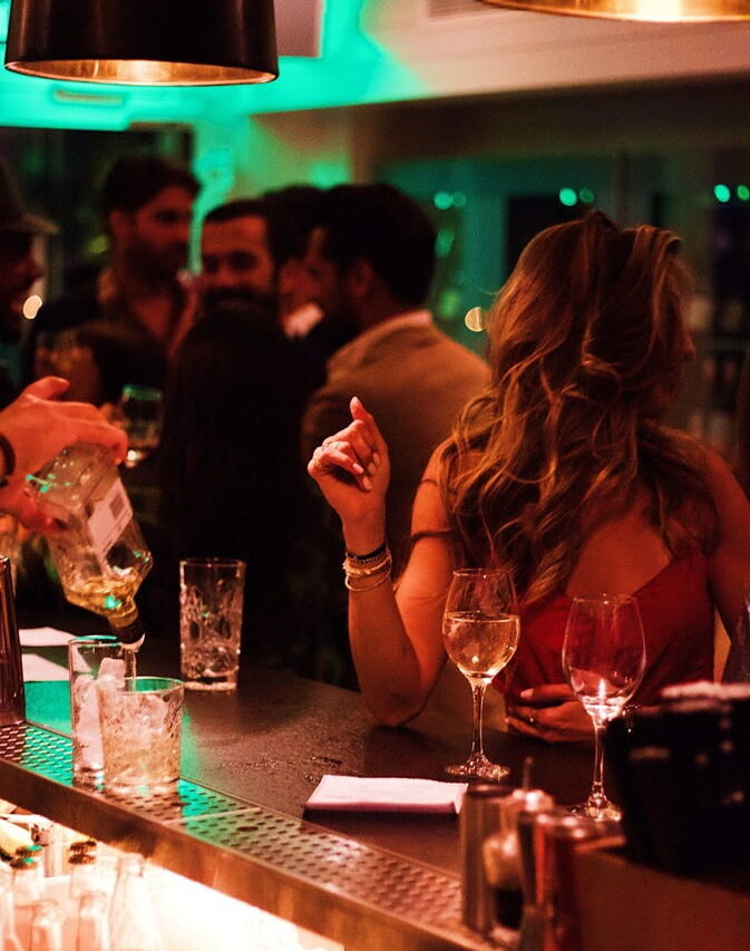 A girl at a bar surrounded by people