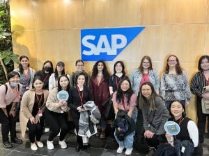 women standing in front of sign that says sap