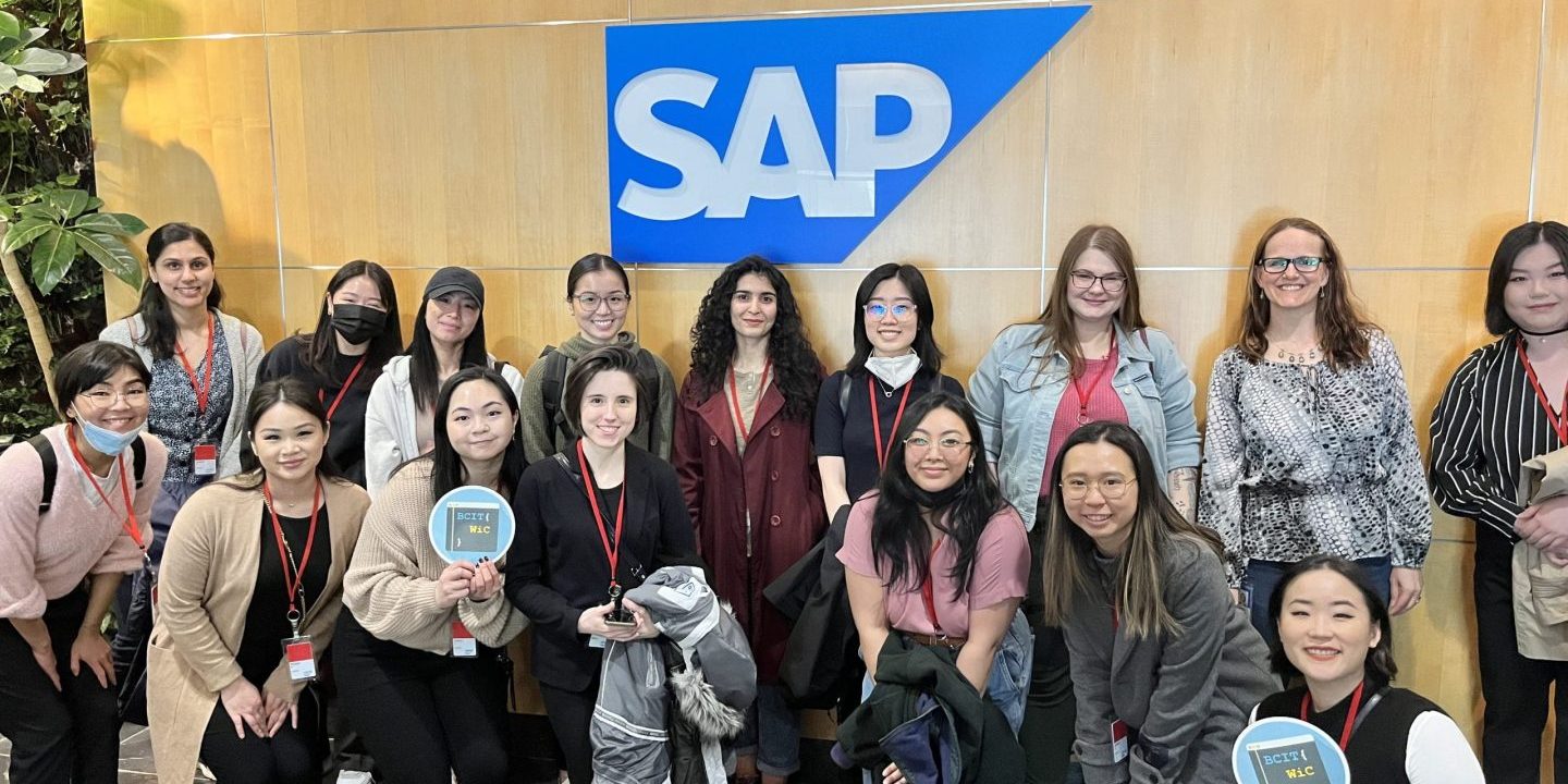 women standing in front of sign that says sap
