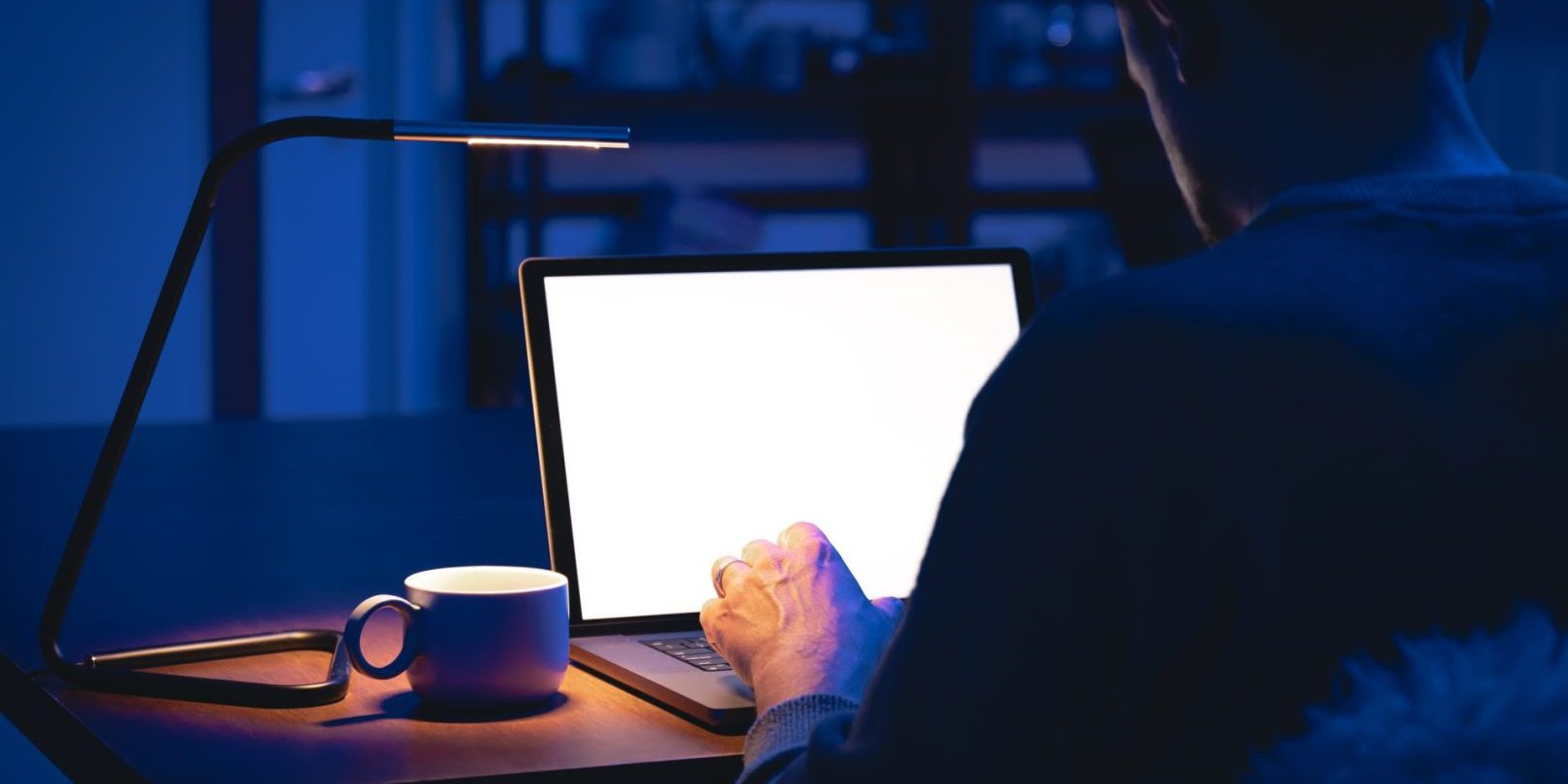 A man works in a dark room, uses a laptop at night.